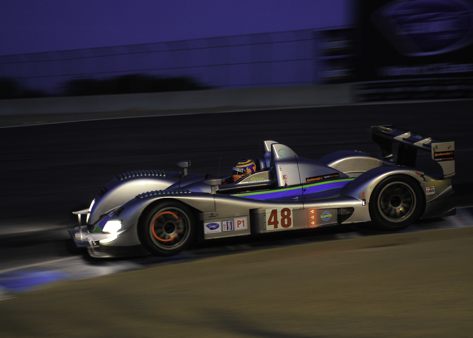 A race car driving down the track at night.