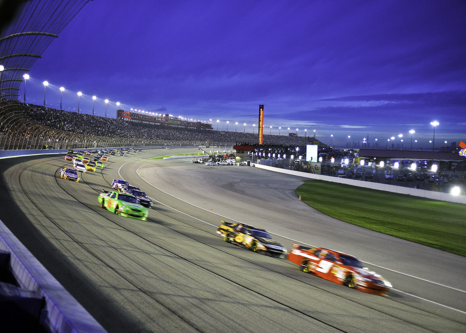 A group of cars racing on a track at night.