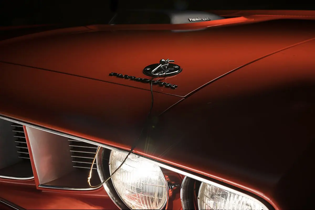 A close up of the hood and headlights on a red car.