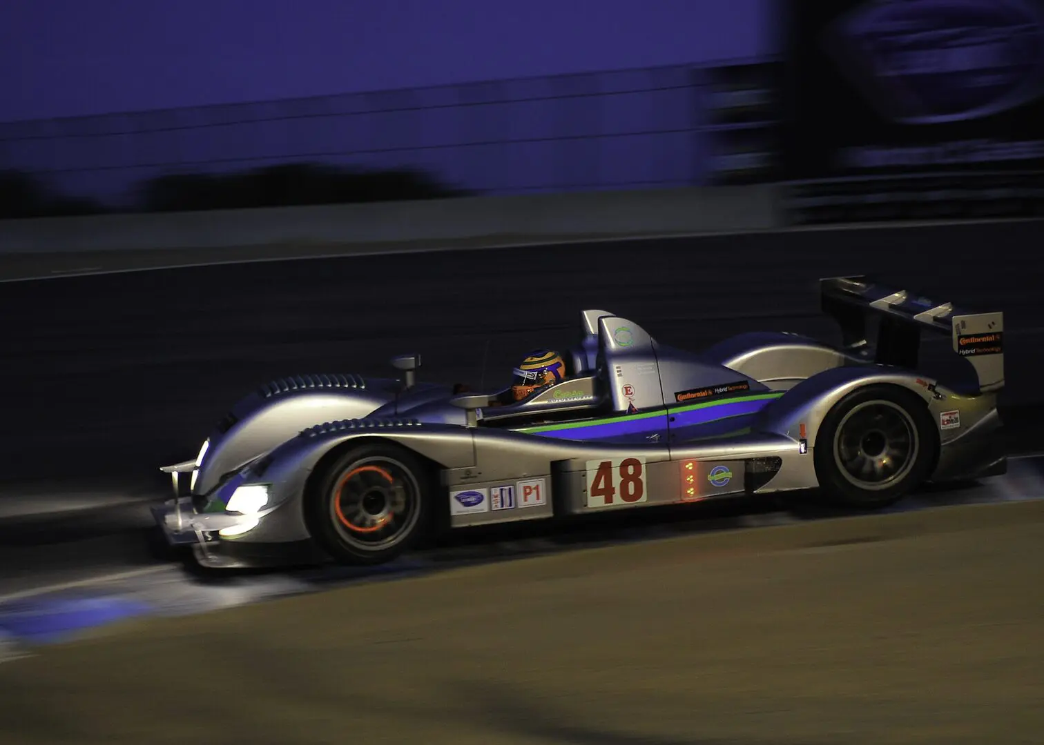 A race car is driving down the track at night.