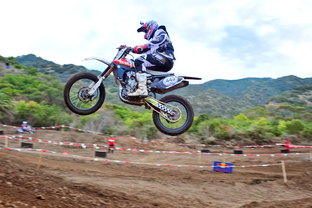 A person on a motorcycle jumping over some dirt.